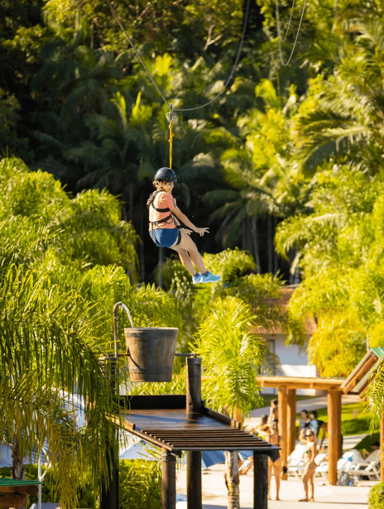 pessoa descendo pela tirolesa com árvores ao fundo